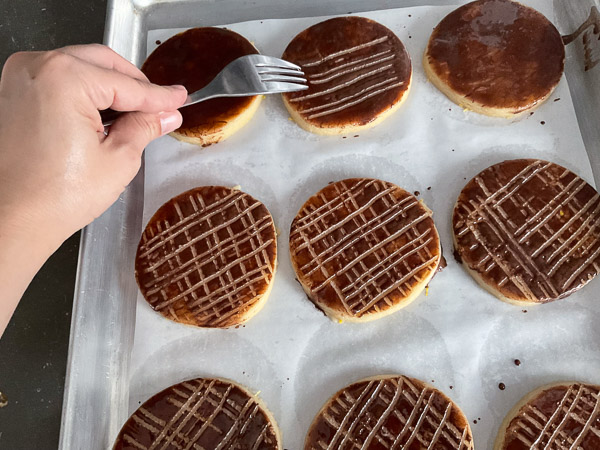 Tracer des lignes parallèles sur le dessus des galettes à l’aide d’une fourchette, puis croiser dans l’autre sens pour créer le motif quadrillé.