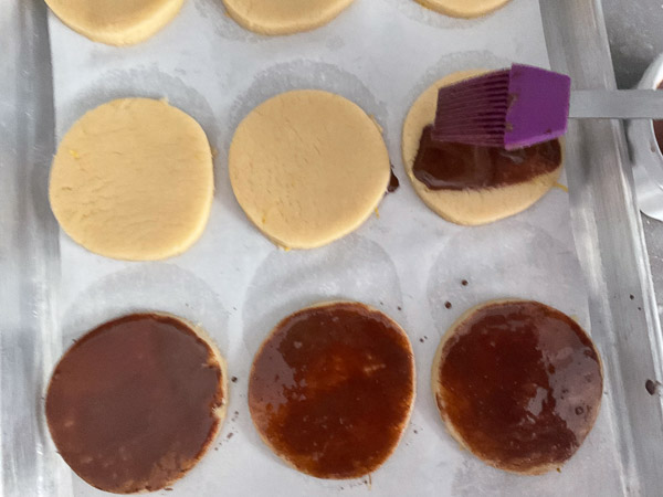 Préparer la dorure en mélangeant le jaune d’œuf, le lait et le cacao, puis badigeonner le dessus des galettes.