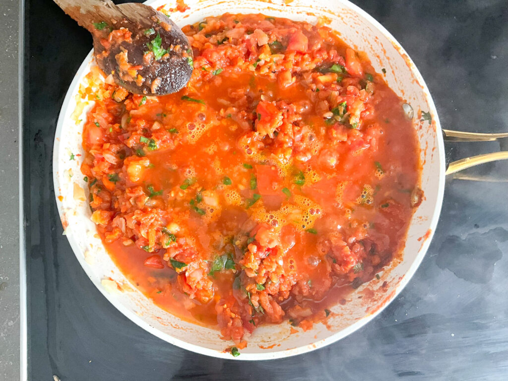 Ajouter les tomates broyées et 1/2 tasse d’eau chaude et laisser mijoter à feu doux jusqu’à obtenir une sauce légèrement épaisse.