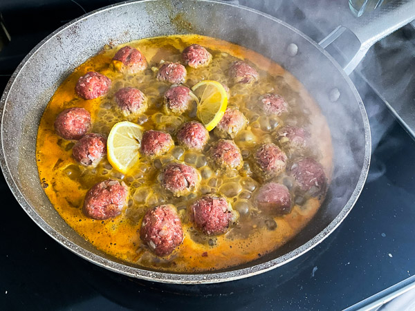 Déposer les boulettes dans la sauce et ajouter les tranches de citron. Couvrir et laisser cuire à feu moyen jusqu’à ce que les boulettes soient bien cuites.