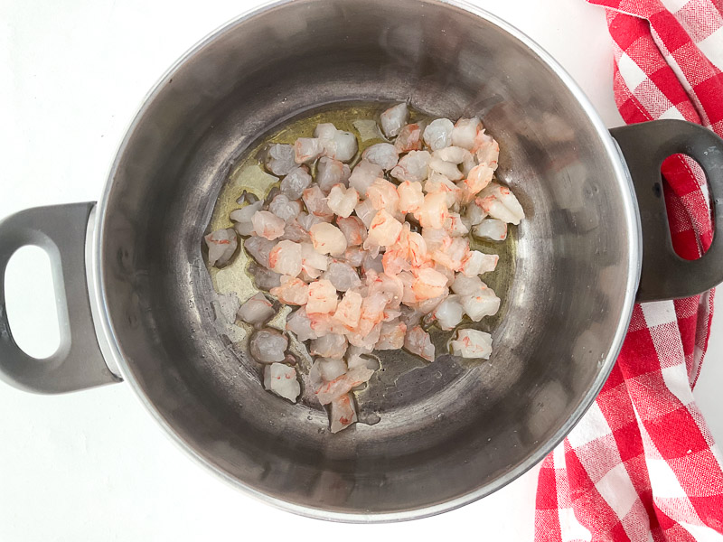 Chauffer un filet d’huile d’olive dans une casserole, puis ajouter les crevettes coupées en petits morceaux et les faire revenir quelques minutes jusqu’à ce qu’elles changent de couleur.