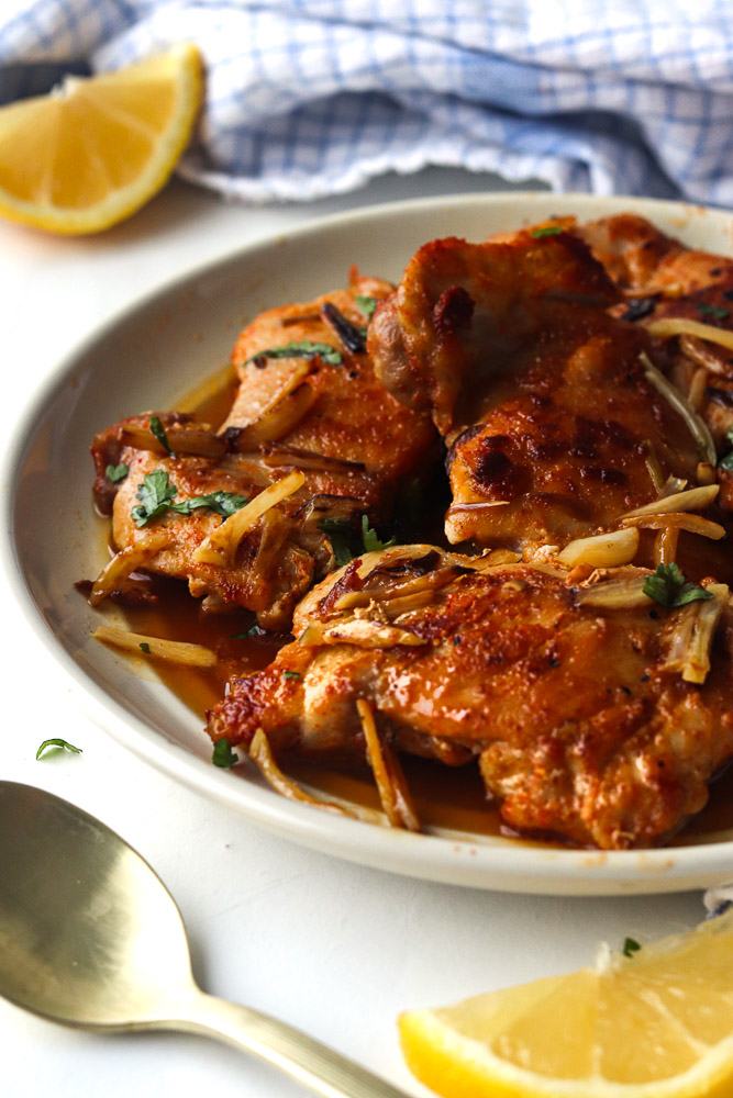 Hauts de cuisses de poulet à l'ail à la poêle servis dans une sauce savoureuse, garnis d'ail doré et de persil frais.
