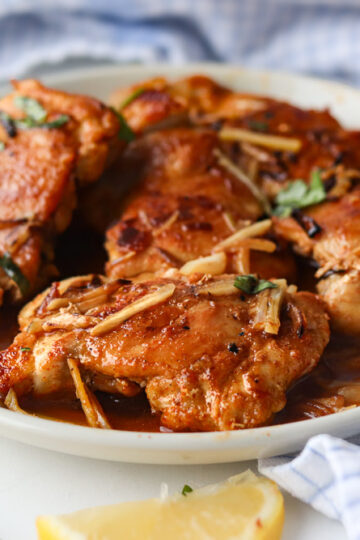 Hauts de cuisses de poulet à l'ail à la poêle servis dans une sauce savoureuse, garnis de bâtonnets d'ail fondants et de persil frais.