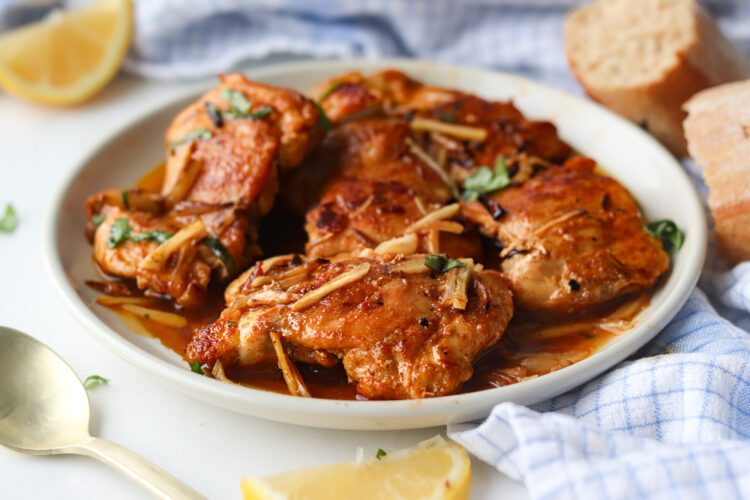 Hauts de cuisses de poulet à l'ail à la poêle servis dans une sauce savoureuse, garnis de bâtonnets d'ail fondants et de persil frais.