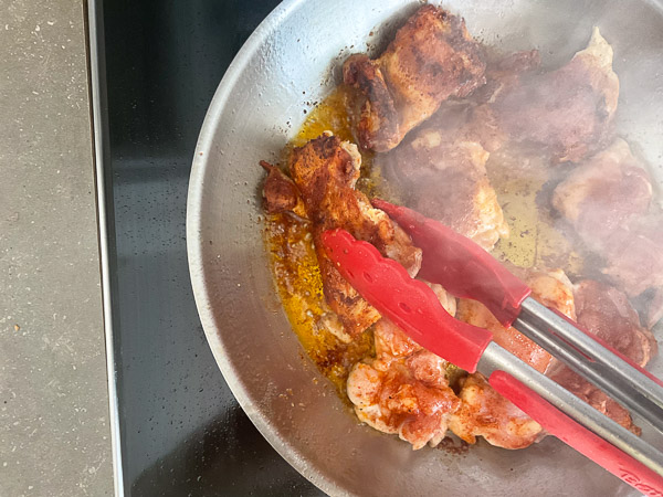Retournez les hauts de cuisses de poulet et poursuivez la cuisson jusqu'à ce qu'ils soient bien dorés des deux côtés.