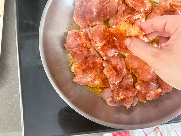 Hauts de cuisses de poulet déposés dans une poêle chaude avec un peu d'huile d'olive.