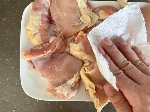 Hauts de cuisses de poulet désossés et sans peau asséchés avec du papier absorbant avant l'assaisonnement.