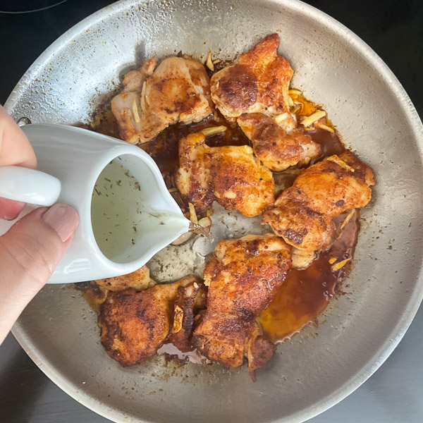 Versez le bouillon de poulet dans la poêle pour déglacer et récupérer toutes les saveurs de cuisson.