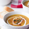 Velouté de légumes lisse avec lentilles rouges, accompagné de pain et d’un linge de cuisine