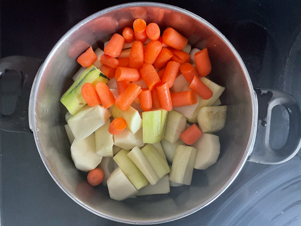 Courgettes, carottes et pommes de terre coupées en morceaux dans une casserole avant cuisson
