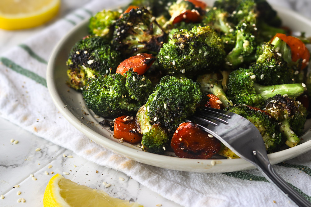 Carottes et brocolis au miel et aux graines de sésame servis dans une assiette, avec des légumes tendres, légèrement croquants et dorés à la poêle.