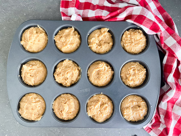 Pâte à muffins au beurre d'arachide répartie dans un moule à 12 cavités avant la cuisson.
