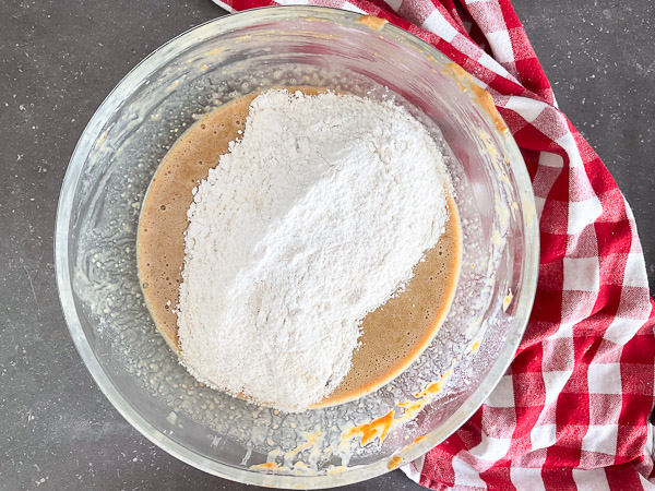 Ajout des ingrédients secs à la préparation liquide pour réaliser des muffins au beurre d'arachide maison.
