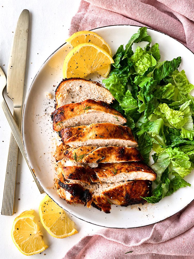 Assiette de poitrine de poulet dorée à l’Air Fryer, coupée en tranches, accompagnée de laitue romaine croquante et de quartiers de citron.