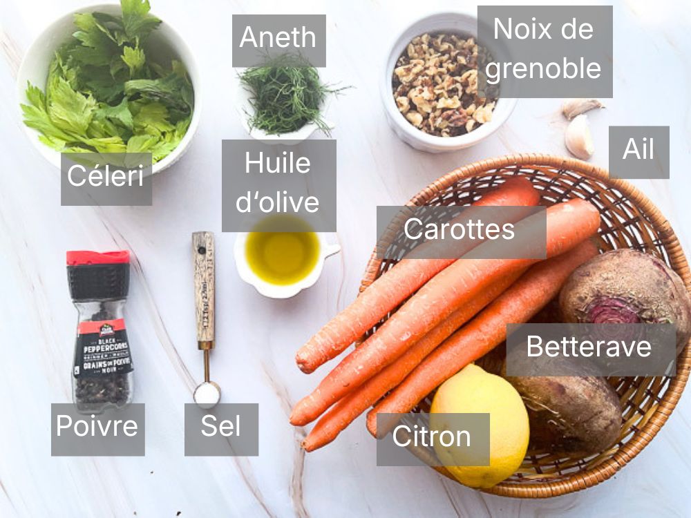 Ingrédients nécessaires pour préparer une salade de betteraves et carottes croquantes aux noix : betteraves crues, carottes, feuilles de céleri, aneth frais, noix de Grenoble, citron, huile d'olive, ail, sel et poivre disposés sur un plan de travail clair.
