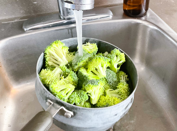 Fleurons de brocoli rincés sous l'eau froide avant d'être séchés et assaisonnés pour la cuisson au Air Fryer.