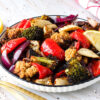 Assiette de légumes marinés rôtis au Air Fryer avec brocoli, chou-fleur, poivron rouge, champignons, oignon rouge et quartiers de citron.