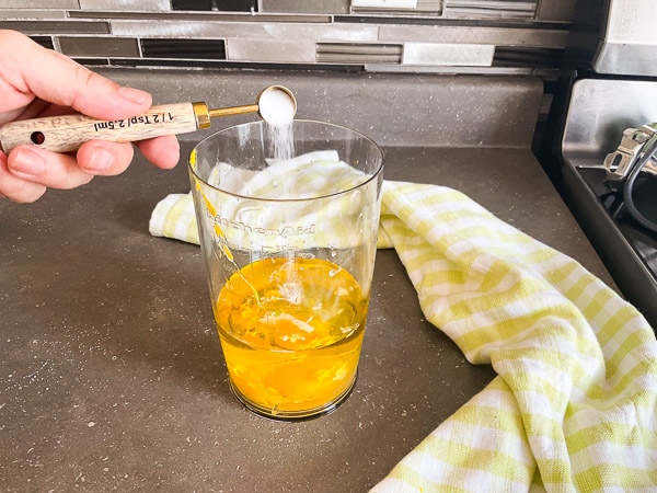 Ajout de sel aux ingrédients de la mayonnaise maison avant le mélange.