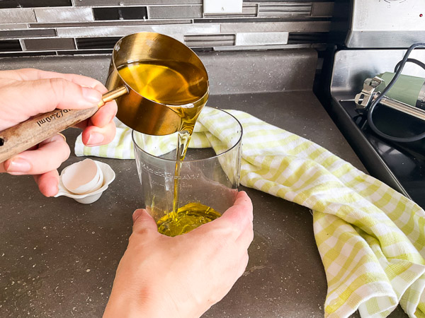 Huile d'olive versée sur l'œuf dans un récipient étroit avant la préparation d'une mayonnaise maison.