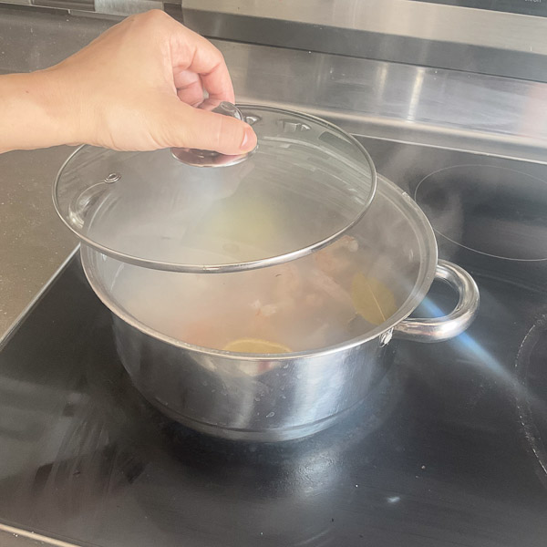 Casserole couverte pendant le pochage des crevettes dans une eau parfumée au citron, au thym et au laurier.