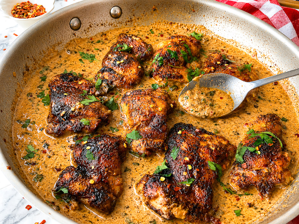 Hauts de cuisse de poulet dorés servis dans une sauce crémeuse épicée aux jalapeños et garnis de persil frais