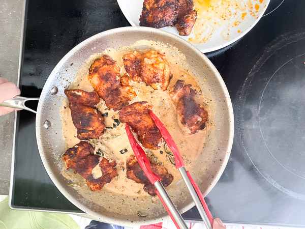 Remise du poulet dans la sauce crémeuse épicée pour terminer la cuisson et l’enrober de saveurs