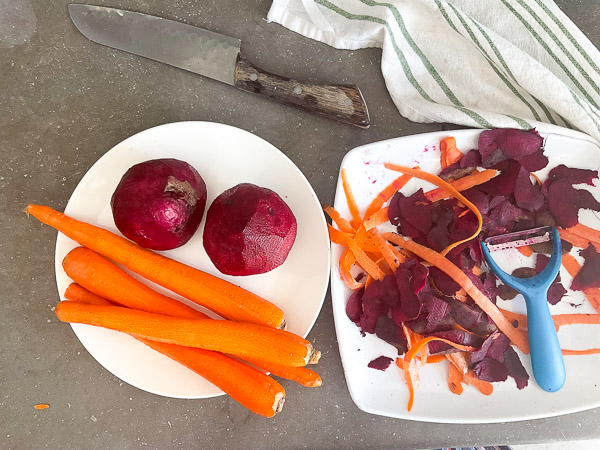 Betteraves crues et carottes pelées prêtes à être transformées en salade croquante sur un plan de travail de cuisine.