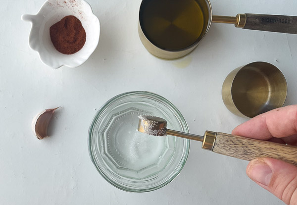 Étape 2 – Ajout du sel dans le vinaigre pour préparer une vinaigrette maison au paprika fumé et à l’ail.