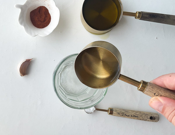 Étape 1 – Vinaigre blanc versé dans un bocal en verre avant le mélange des ingrédients de la vinaigrette au paprika fumé et à l’ail.